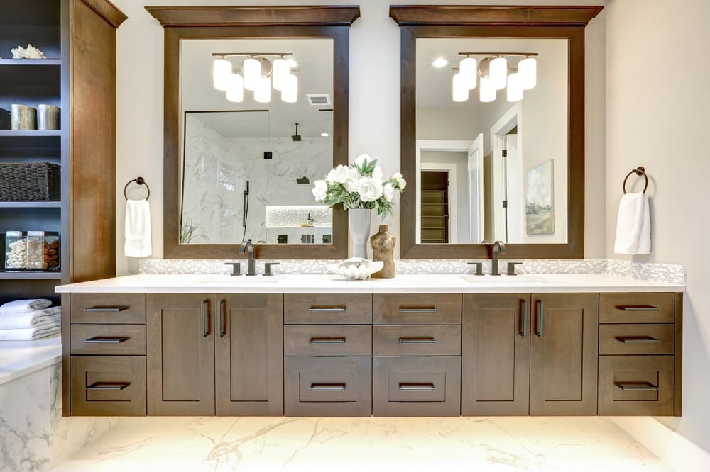 brown custom bathroom vanities Chicago with dark grey handles and two large wooden mirrors